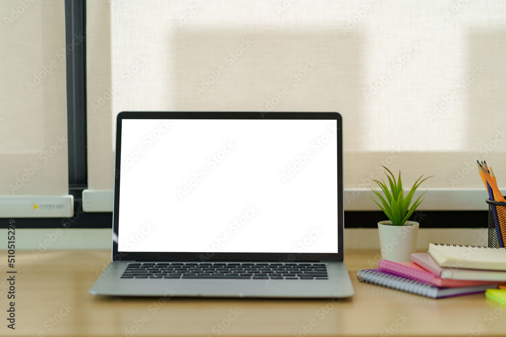 Poster laptop computer with blank white screen on table in the office. mock up.