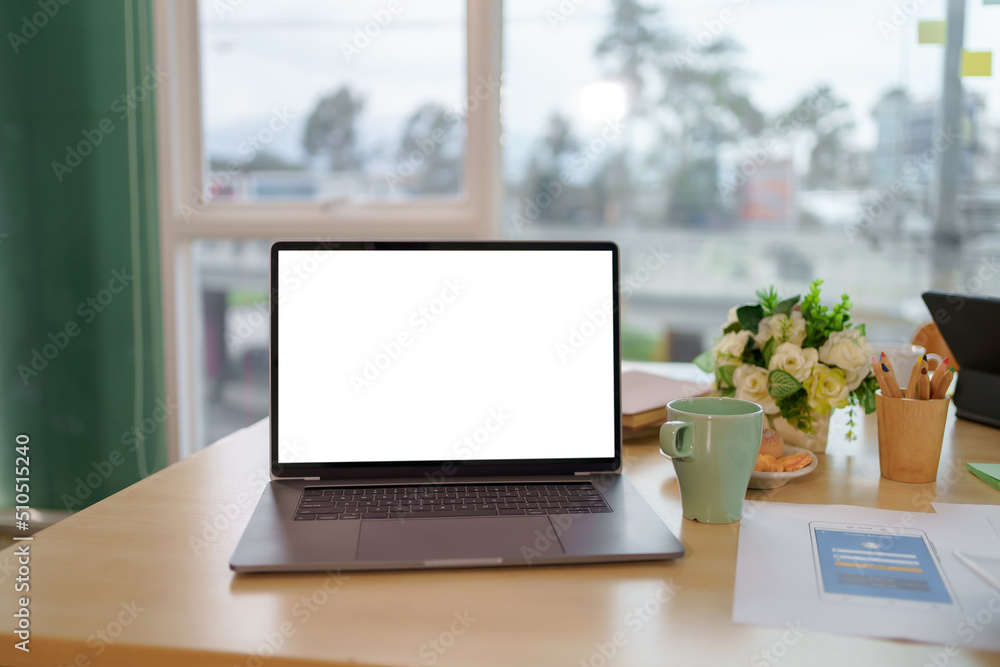 Poster laptop computer with blank white screen on table in the office. mock up.