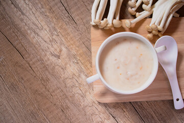 Mushroom cream soup in a white cup on the wooden floor.