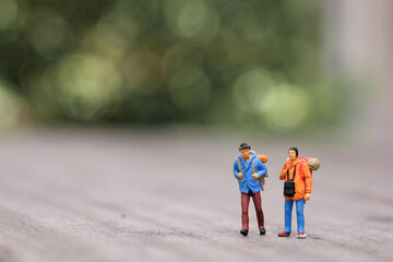 Miniature figures of two travellers or backpackers with copy space in a concept of vacations, travel and tourism.