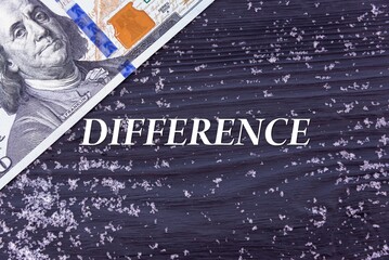 DIFFERENCE - word (text) on a dark wooden background, money, dollars and snow. Business concept (copy space).