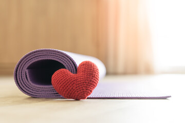 Red yarn heart shape and yoga mat at home floor. Be ready to exercise indoors for good health.