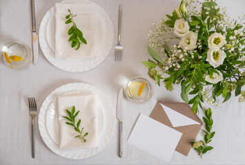 Wedding teble decoration with white flowers, glasses and white napkins. Wedding invitation card template. Elegantly decorated table at a wedding reception. Festive table setting.