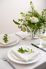 Wedding teble decoration with white flowers, glasses and white napkins. Elegantly decorated table at a wedding reception. Festive table setting. The wedding decor.