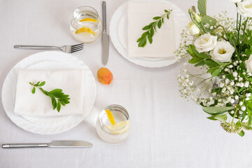 Wedding teble decoration with white flowers, glasses and white napkins. Elegantly decorated table at a wedding reception. Festive table setting. The wedding decor.