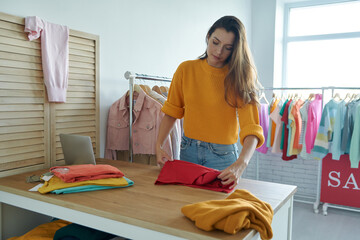 Attractive young woman working in her own fashion store