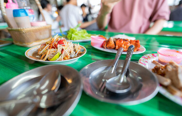 Spicy green papaya salad or Som Tum with Thai rice noodles. Street food with hot and spicy dish in Thailand. The famous local Thai street food. Thai Esarn cuisine. Papaya salad with grilled chicken.