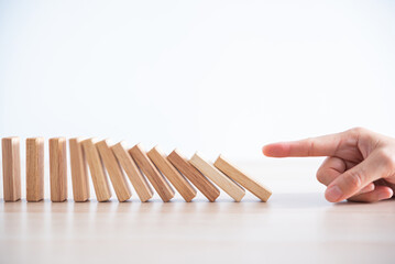 woman hand start wooden block tower stack crash or fall domino  ,financial business and risk management