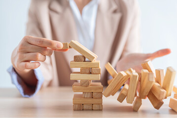 business female hand building a wooden block tower but failed , risk and strategy of project management , business and strategy concept