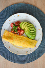 French omelet filled with cheese. Plating with avocado and cherry tomatoes.