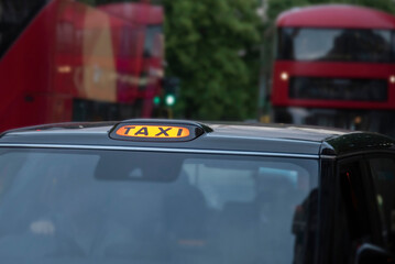 Taxi sign lit in traffic at night.