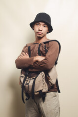 Portrait of young Asian boy with sad expression wearing black hat and carrying backpack in front