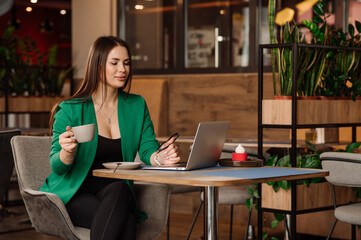 Sexy female blogger or freelancer is working with a laptop in the cafe or coworking area