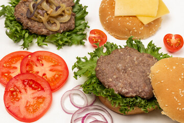 Fried burger bun on lettuce leaf, fried burger with cheese and fried onions, chopped tomatoes and onions.