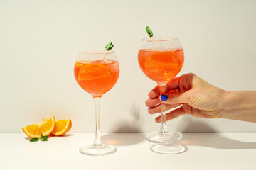 Concept of summer alcohol drink, female hand holds Aperol Spritz