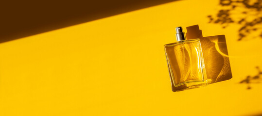 Transparent bottle of perfume on a yellow background. Fragrance presentation with daylight. Trending concept in natural materials with beautiful shadow. Women's essence. - obrazy, fototapety, plakaty