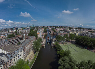 Fototapeta na wymiar Aerial drone panoramic view of a ship passing elevating road bridge in amsterdam canal. Ship under open bridge over the canal.
