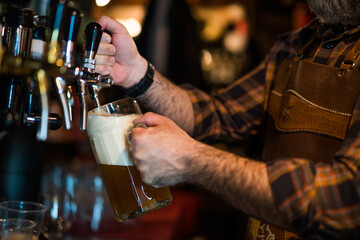 Close up of barmen pours beer into a beer glass at pub.
