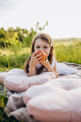 Fototapeta premium Little girl portrait eating red apple outdoor