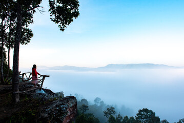 Traveler Asian woman enjoying and relaxing on the mountains view containing calm, fog, and mist in the morning.