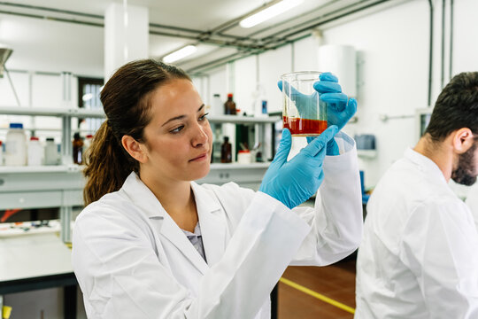 Serious chemist examining liquid in flask in lab