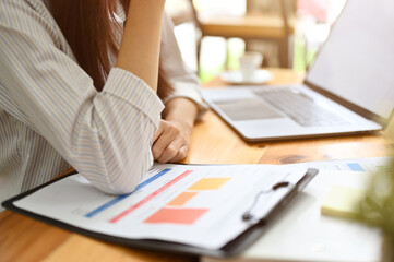 Cropped, close-up image, Businesswoman working at her office desk, reading a financial report.