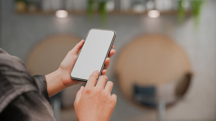 A female hand holding a smartphone over blurred coffee shop in the background.