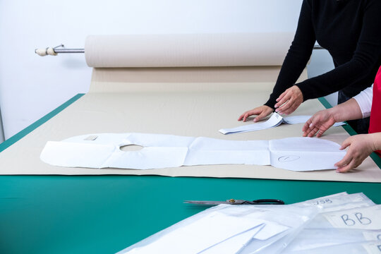 Unrecognizable seamstresses working with paper patterns in studio