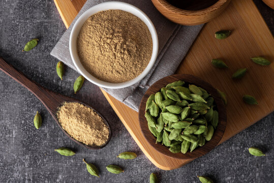 Green cardamom in wooden bowl and spoon. Dry cardamom spice. Cardamom seeds macro shot.