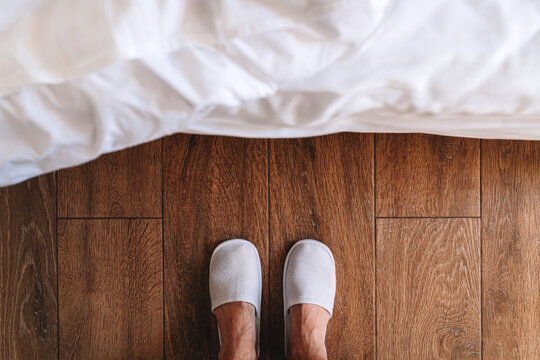 Male Feet In White Hotel Slippers Standing In Front Of The Bed