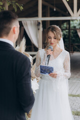 Beautiful space wedding ceremony in the summer of a chic couple, the groom in a suit and the bride in a white luxurious wedding dress.