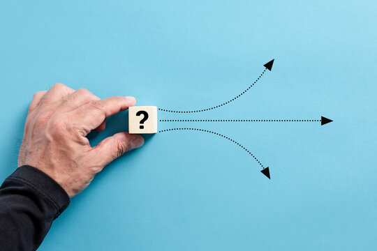 Male hand puts a wooden cube with question mark. Different solution alternatives for an emerging problem or alternative path options.