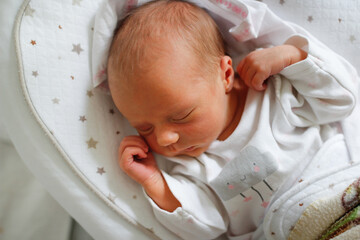 Gentle innocent newborn baby sleeps on light baby cocoon