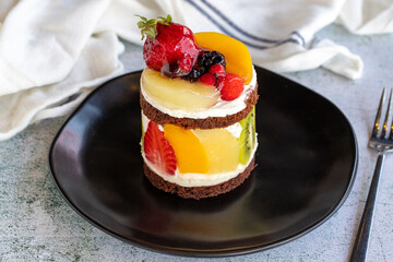 Fruit cake. Cake surrounded by fruits on a stone background. Patisserie products. Close-up.