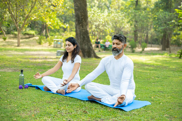 Two indian male and female person do yoga mediation exercise together in the park outdoor. Healthy lifestyle, Sports and workout concept,