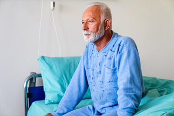 Thoughtful senior male patient in hospital bed in ward room. Healthcare people problem concept