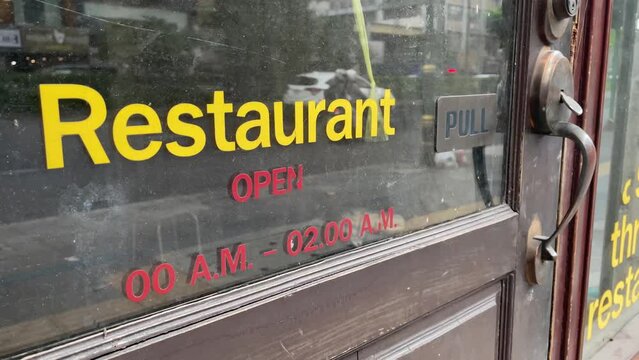Restaurant sticker sign on glass door storefront. Closed store with traffic on road - day