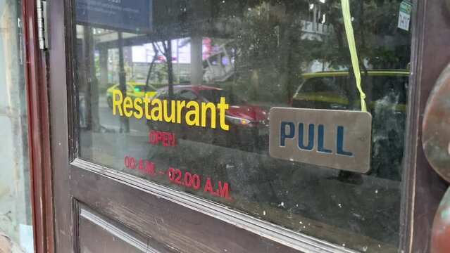 Restaurant sticker sign on glass door storefront. Closed store with traffic on road - day