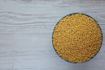 Raw Organic Stelline Pasta in a Bowl on a white wooden background, top view. Flat lay, overhead,...