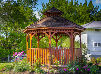 Wooden pergola at the beautiful green garden with flowers.