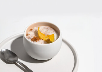 Close up of Creamy rice pudding decorated with lemon slice and cinnamon aon white background.  Healthy homemade dessert