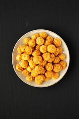 Homemade Crumbly Biscuits with Parmigiano Reggiano on a Plate on a black surface, top view. Flat lay, overhead, from above.