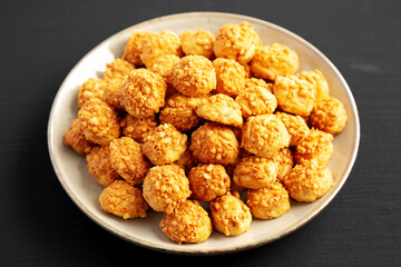 Homemade Crumbly Biscuits with Parmigiano Reggiano on a Plate on a black background, side view. Close-up.