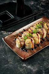 Baked roll with eel and unagi sauce in a brown plate