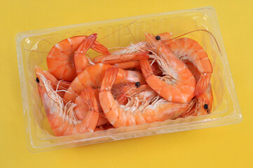 Barquette en plastique de crevettes en gros plan sur fond jaune