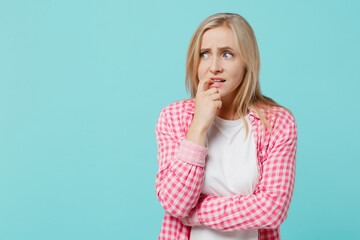 Young caucasian worried sad confused woman she 30s in pink shirt white t-shirt look aside biting nails fingers isolated on plain pastel light blue background studio portrait. People lifestyle concept.