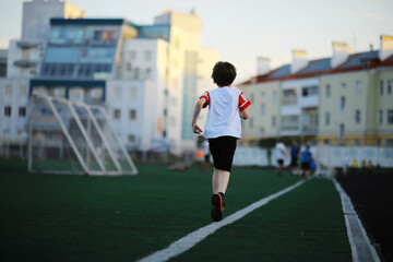 Fototapeta premium The child goes in for sports at the stadium. The boy is training before playing football.