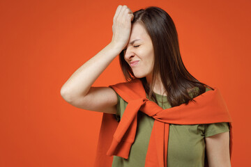 Young sad woman 20s wear khaki t-shirt tied sweater on shoulders put hand on face facepalm epic fail mistaken omg gesture isolated on plain orange background studio portrait. People lifestyle concept.