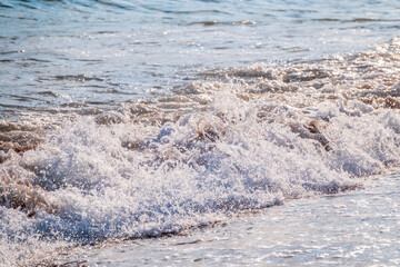 Splashes of water and foam against the sea on a sunny summer day