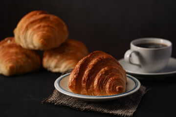 Close up view butter croissants and cup of coffee on wooden table. Levitation, bread bakery products cafe concept